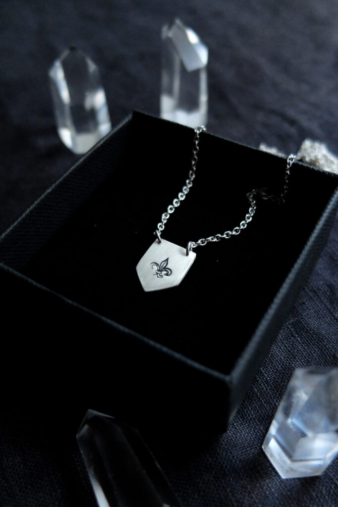 shield shaped pendant stamped with a fleur de lys stamp, with crystals