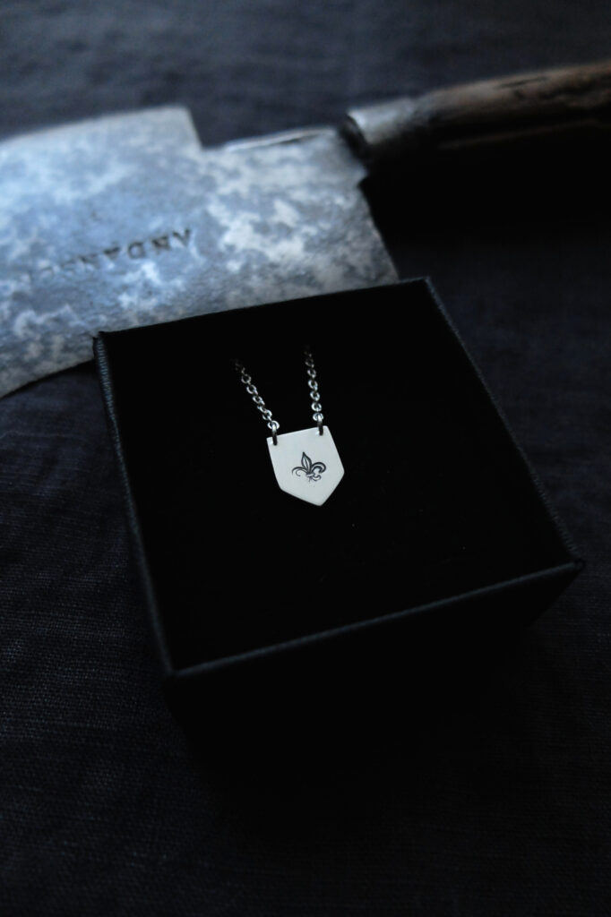 shield shaped pendant with a fleur de lys stamp
