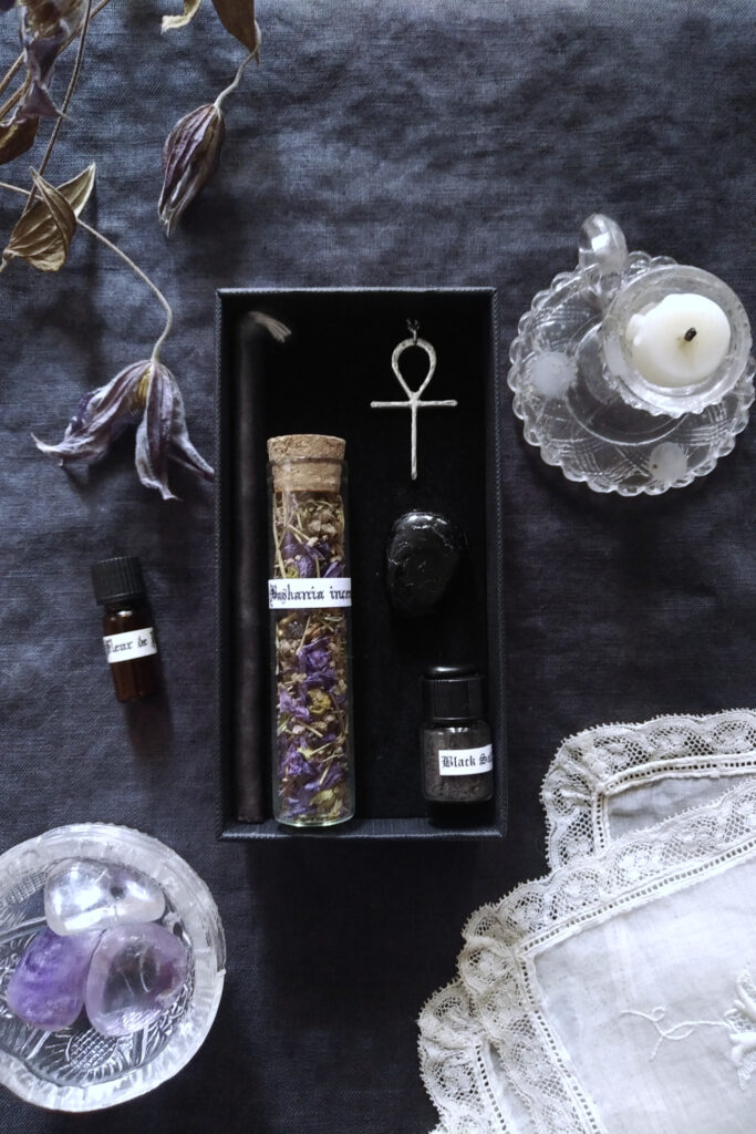Mini candle, mini vials and black tourmaline, Ankh silver necklace, on dark fabric, with candkle