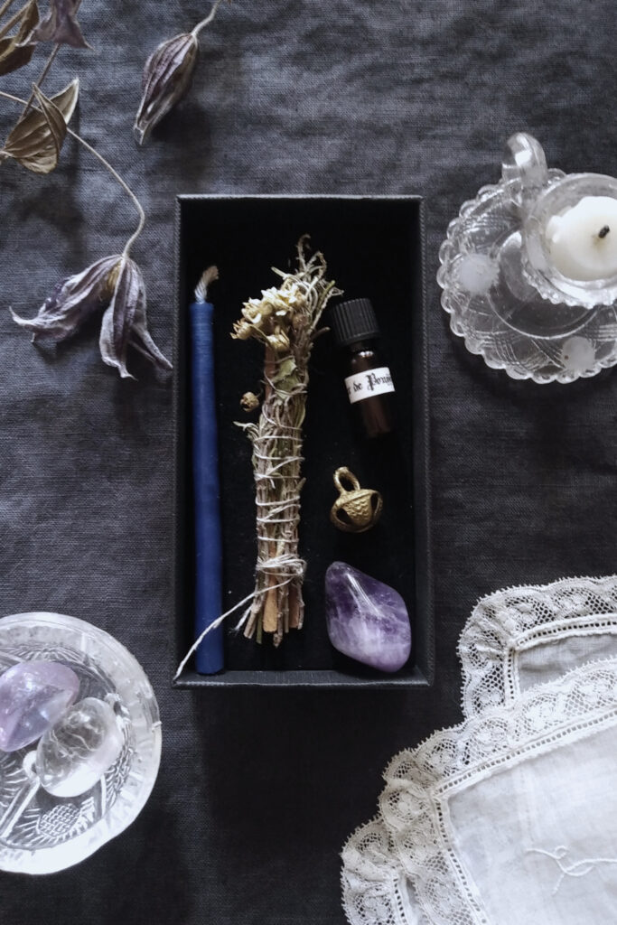 Mini candle, mini vial, bell and amethyst, on dark fabric, with antique lace handkerchief