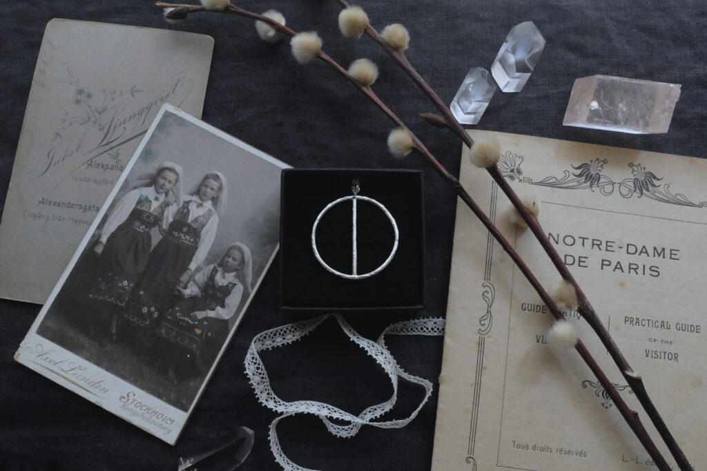 silver pendant of the alchemical symbol Antiony with antique photos and a "Notre Dame de Paris" booklet