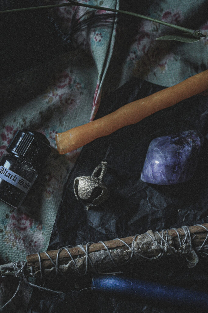 dark still life with black salt, bell, amethyst and a mini candle