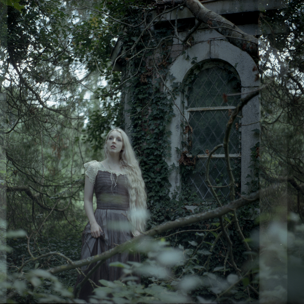 Sylvaine next to an abandoned chapel with stained-glass window