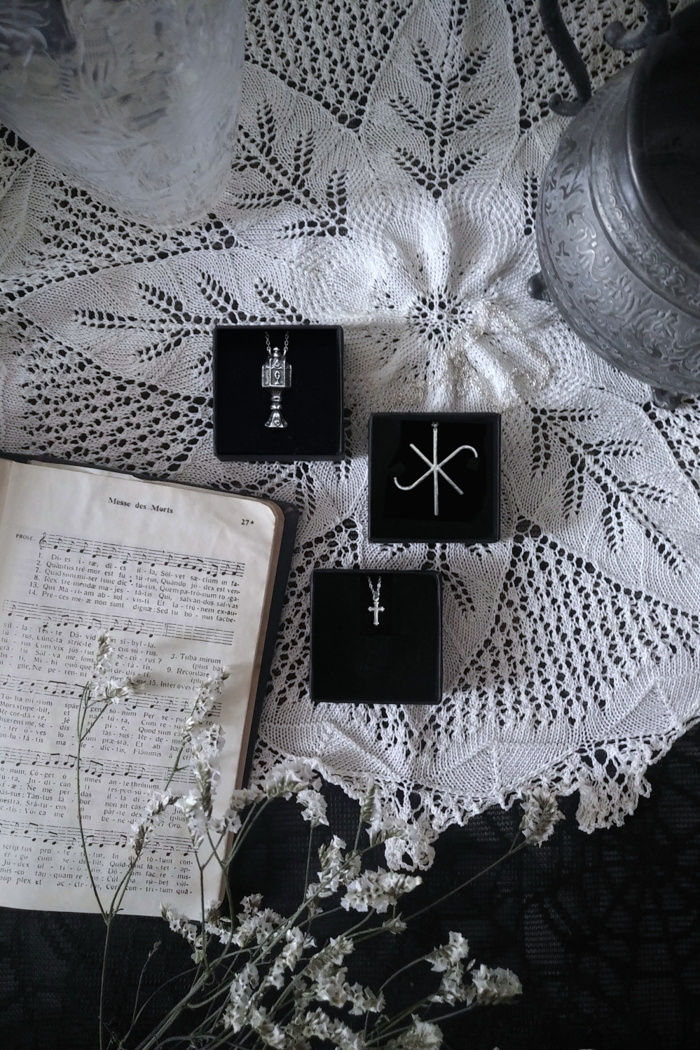 Collection of silver jewels inspired by the middle-ages: crucifix, holy grail and Hildegard von Bingen Litterae Ignotae on a doily