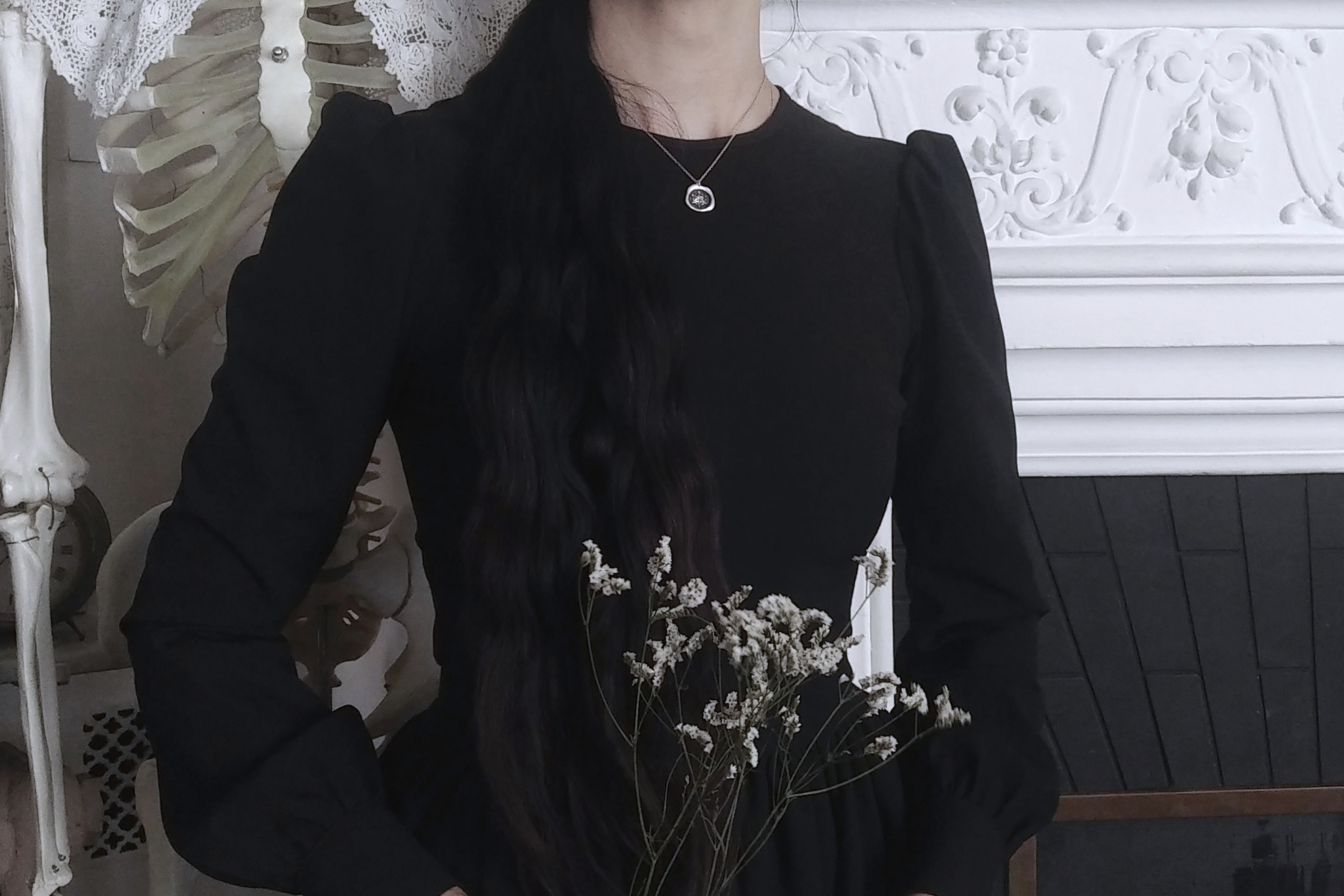 Woman in black dress wearing a Silver wax-seal inspired jewel, with a Daisy Wheel / witches mark
